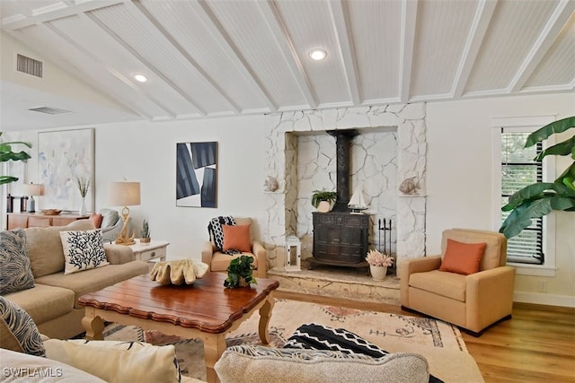 living room featuring lofted ceiling, hardwood / wood-style flooring, and a wood stove