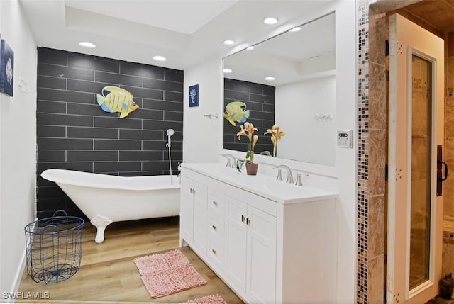 bathroom featuring tile walls, a raised ceiling, vanity, and hardwood / wood-style floors