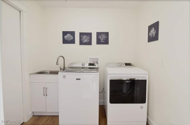 washroom with separate washer and dryer, cabinets, sink, and wood-type flooring