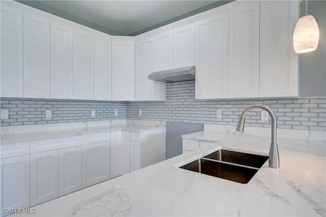 kitchen featuring white cabinets, sink, decorative backsplash, decorative light fixtures, and light stone counters