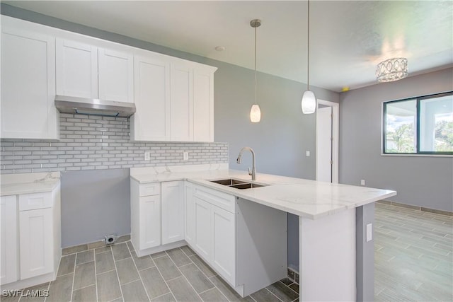 kitchen with white cabinets, sink, decorative backsplash, decorative light fixtures, and kitchen peninsula