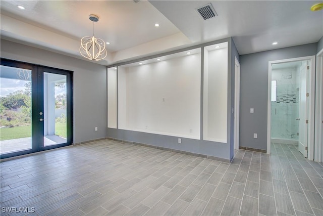 spare room with french doors and a notable chandelier