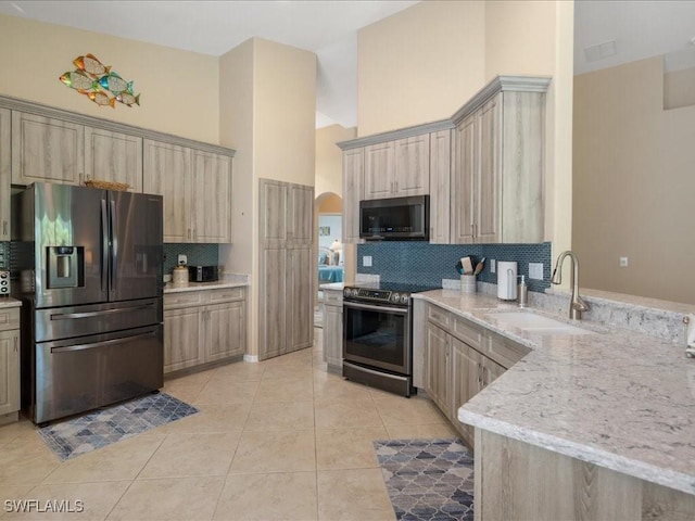 kitchen featuring backsplash, stainless steel appliances, sink, light tile patterned floors, and a high ceiling