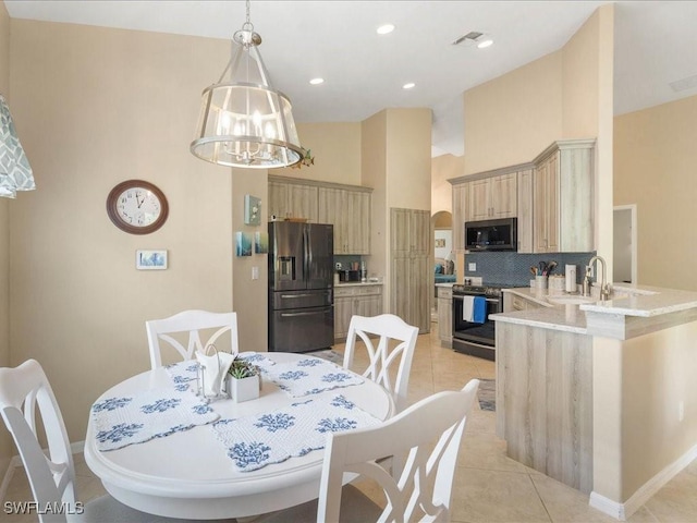 tiled dining space featuring sink, a high ceiling, and a notable chandelier