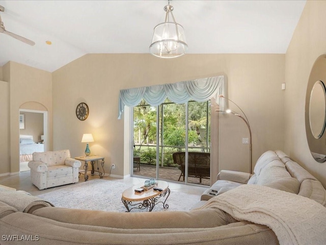 carpeted living room with ceiling fan with notable chandelier and vaulted ceiling