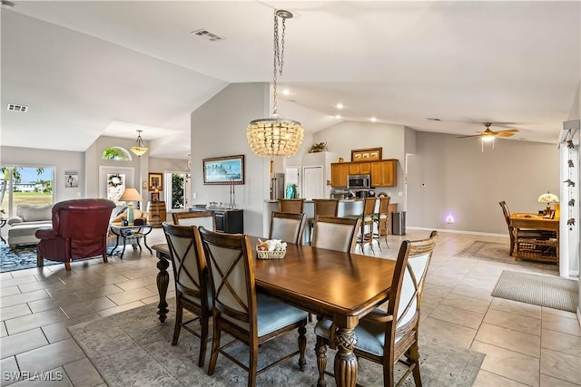 tiled dining space featuring ceiling fan with notable chandelier and vaulted ceiling