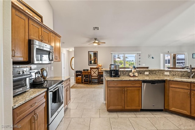 kitchen with sink, ceiling fan, light stone countertops, appliances with stainless steel finishes, and light tile patterned flooring