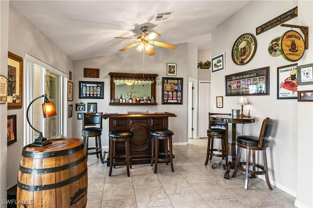 bar featuring light tile patterned floors, ceiling fan, and lofted ceiling