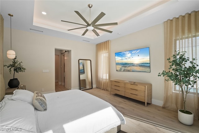 bedroom featuring a raised ceiling, ceiling fan, and light hardwood / wood-style floors