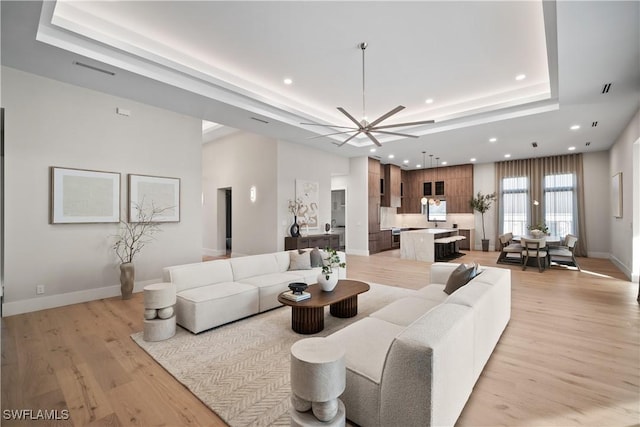 living room with a tray ceiling and light hardwood / wood-style flooring