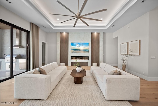 1364 Cypress Woods Dr, Naples, FL 34103 - living area with wood finished floors, a raised ceiling, a fireplace, a ceiling fan, and baseboards