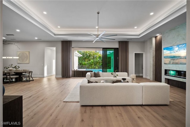 living room with a large fireplace, ceiling fan, and light hardwood / wood-style flooring