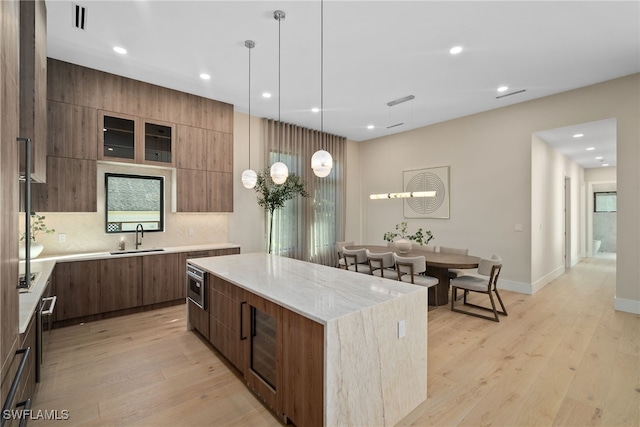 1364 Cypress Woods Dr, Naples, FL 34103 - kitchen with modern cabinets, a center island, a sink, light wood finished floors, and recessed lighting