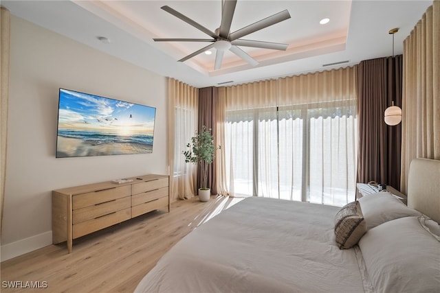 bedroom featuring light hardwood / wood-style floors, a raised ceiling, and ceiling fan