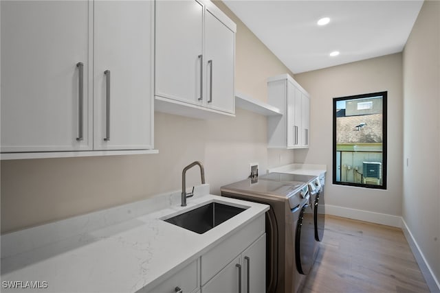 laundry area featuring cabinets, sink, washer and dryer, and light wood-type flooring