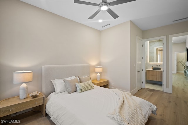 bedroom with ensuite bathroom, ceiling fan, and wood-type flooring