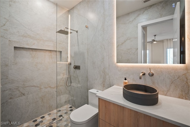 bathroom with tiled shower, vanity, toilet, and ceiling fan