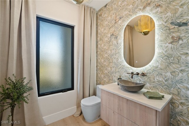 1364 Cypress Woods Dr, Naples, FL 34103 - bathroom with wallpapered walls, toilet, vanity, and wood finished floors