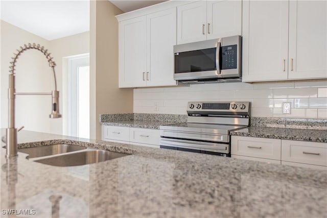 kitchen featuring sink, tasteful backsplash, light stone counters, white cabinetry, and stainless steel appliances