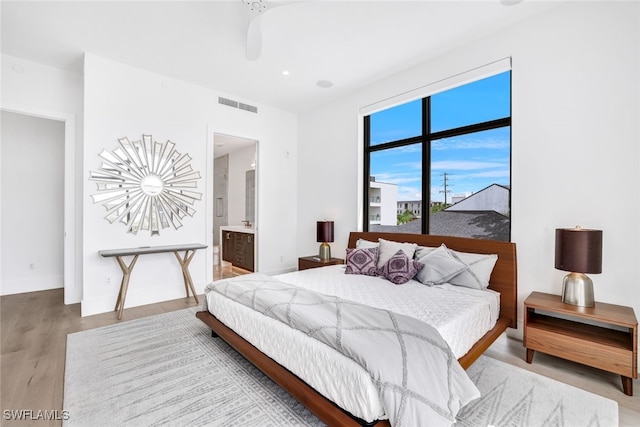 bedroom with connected bathroom, ceiling fan, and hardwood / wood-style floors