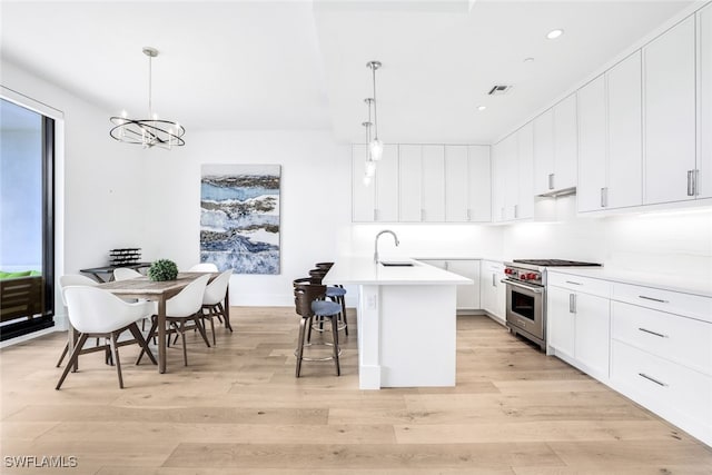 kitchen featuring pendant lighting, luxury stove, white cabinetry, and a kitchen island with sink