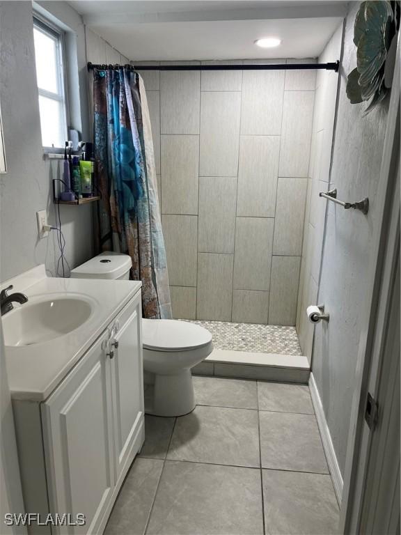 bathroom featuring a shower with shower curtain, tile patterned flooring, toilet, and vanity