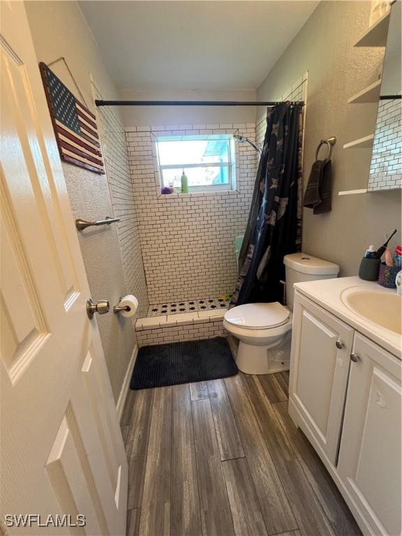 bathroom with hardwood / wood-style flooring, a shower with curtain, toilet, and vanity