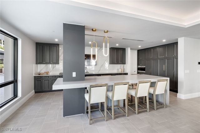 kitchen with a breakfast bar, light countertops, backsplash, and decorative light fixtures