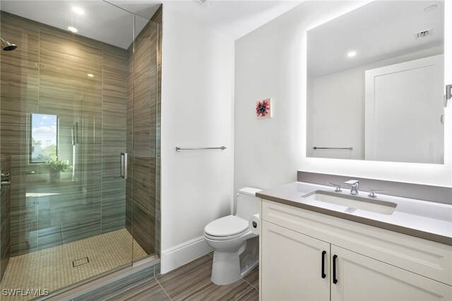 bathroom with a stall shower, baseboards, visible vents, toilet, and vanity