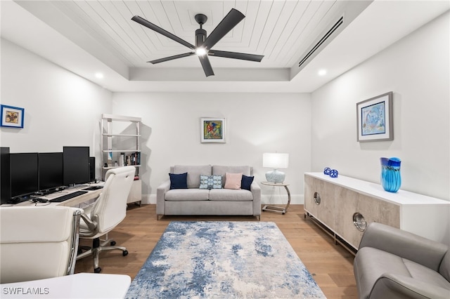 office space with light wood-style floors, baseboards, visible vents, and a raised ceiling