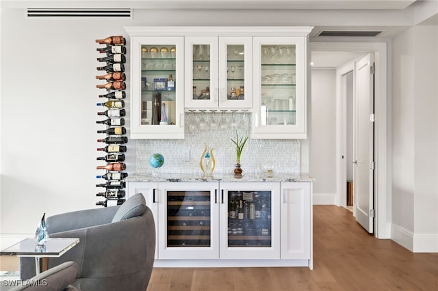 bar with tasteful backsplash, beverage cooler, visible vents, and a bar