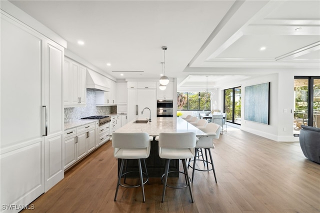 kitchen featuring stainless steel appliances, premium range hood, pendant lighting, and white cabinets