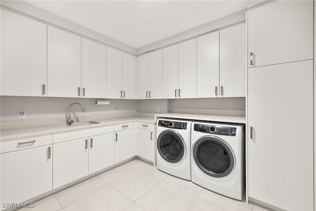 laundry area with washer and dryer, cabinet space, a sink, and light tile patterned floors