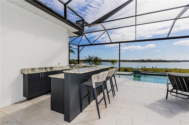 view of patio with a swimming pool with hot tub, a water view, and an outdoor bar