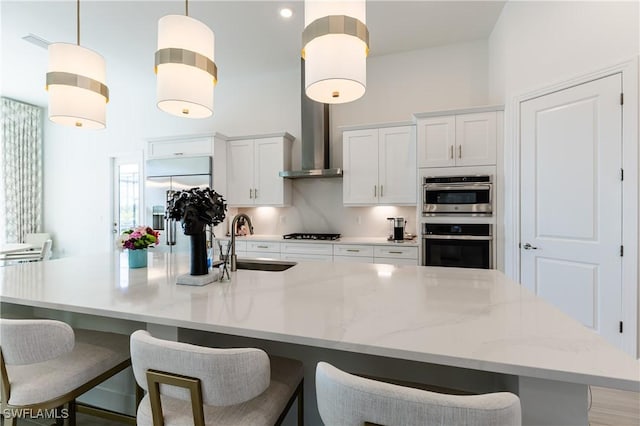 kitchen featuring a large island, decorative light fixtures, white cabinetry, and sink