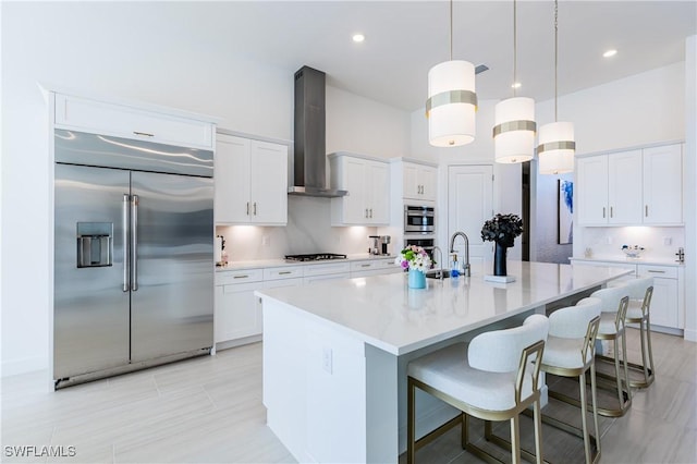 kitchen featuring pendant lighting, wall chimney exhaust hood, white cabinetry, and built in refrigerator