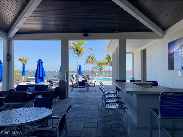 view of patio / terrace featuring a water view, exterior bar, and a community pool