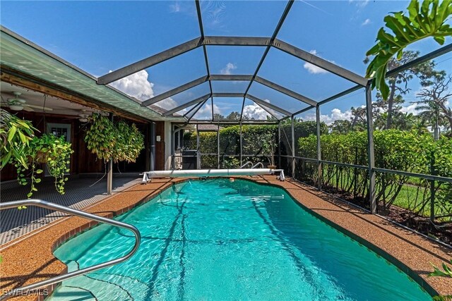 view of swimming pool featuring ceiling fan and a lanai