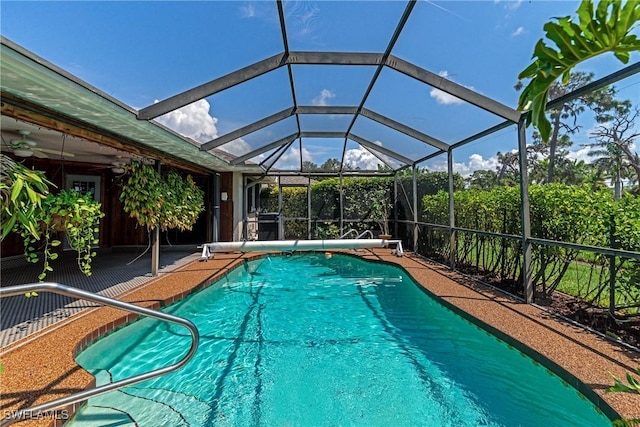 view of swimming pool with ceiling fan and glass enclosure