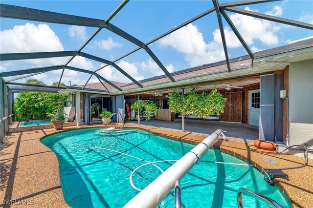 view of swimming pool featuring a patio, glass enclosure, a hot tub, and ceiling fan