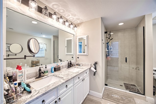 bathroom featuring a sink, a shower stall, baseboards, and double vanity