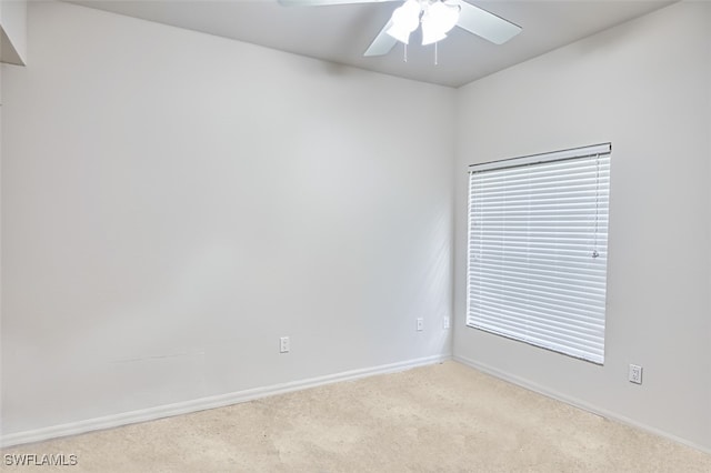 spare room with light colored carpet, ceiling fan, and baseboards