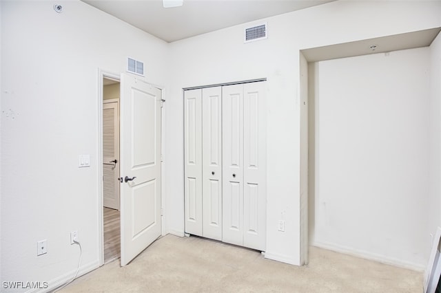 unfurnished bedroom featuring a closet, visible vents, and light carpet