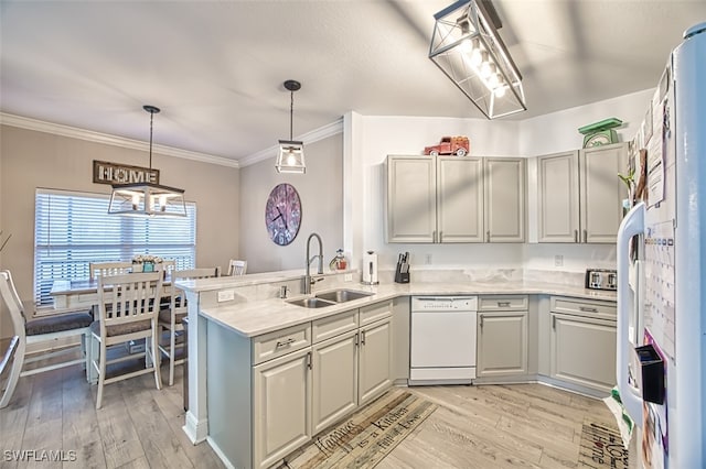 kitchen with a peninsula, hanging light fixtures, white dishwasher, light countertops, and a sink