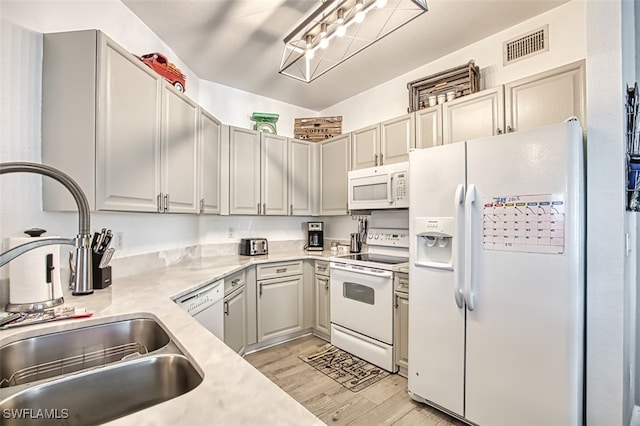 kitchen featuring sink, white appliances, and light wood-type flooring