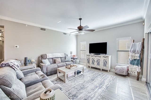 living area featuring light wood-style flooring, visible vents, and crown molding