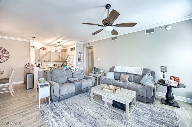 living room featuring light wood-style floors, visible vents, crown molding, and baseboards