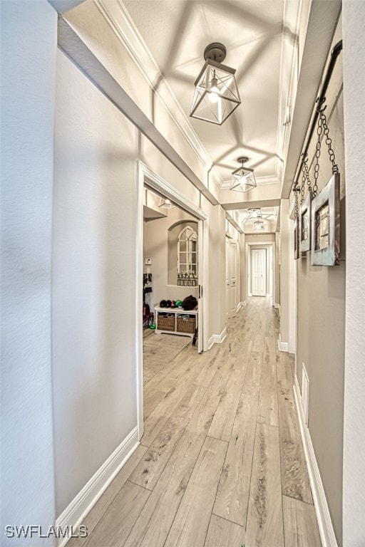 hall featuring light wood finished floors, baseboards, and ornamental molding