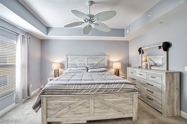 bedroom with baseboards, a raised ceiling, and light colored carpet