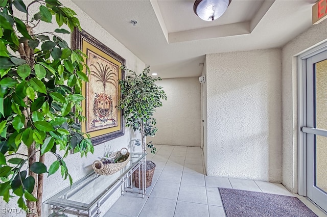 interior space featuring light tile patterned floors and a raised ceiling